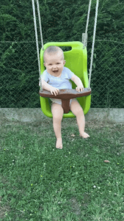 Baby Smiling On Green Swing In Grass GIF