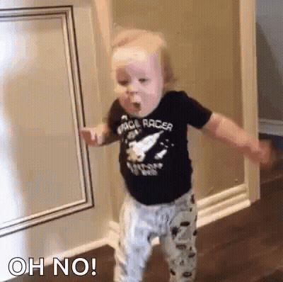 Baby Standing In Hallway Eating With Arms Outstretched GIF