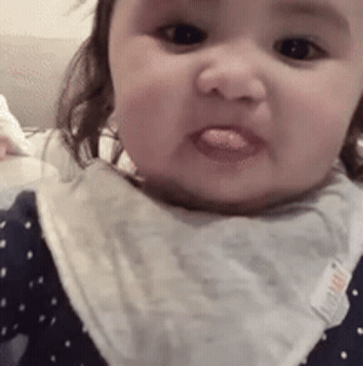 Baby Sticking Tongue Out Wearing Bib GIF