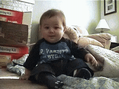 Baby Wearing R. Varsity Byga Shirt Sitting On Bed GIF
