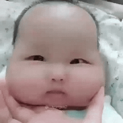 Baby With Large Head Held Making Funny Face GIF