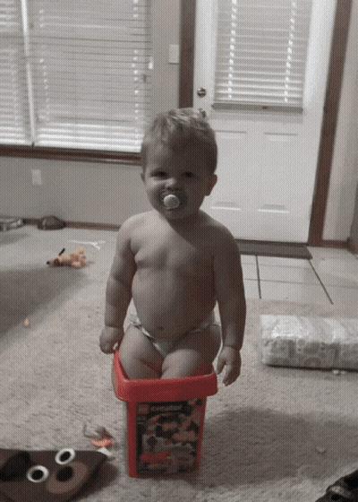Baby With Pacifier Sitting in Bucket