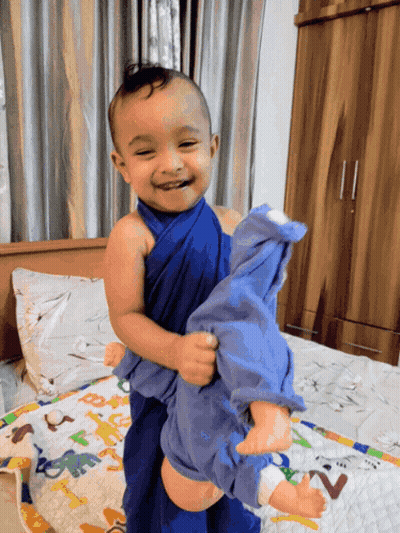 Baby Wrapped In Blue Holding Doll GIF