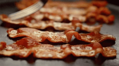 Bacon Is Being Sliced On A Pan With A Fork . GIF