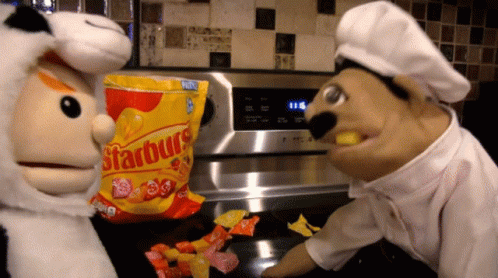 Bag Of Starburst On Counter Next To Two Puppets GIF