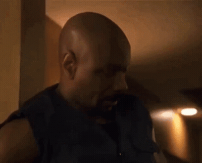 Bald Bearded Man Standing In Dark Room GIF