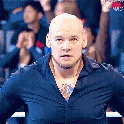 Bald Bearded Man With Chest Tattoo Facing Crowd In Boxing Ring GIF