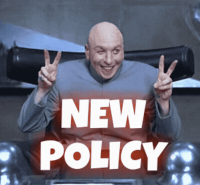 Bald Man Giving Peace Sign In Front Of New Policy Sign GIF