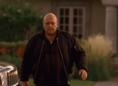 Bald Man In Black Jacket In Front Of House GIF