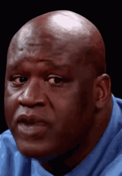 Bald Man In Blue Shirt Looking At Camera GIF