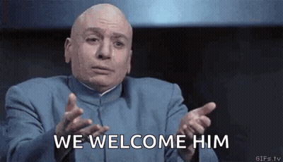 Bald Man In Blue Suit Saying We Welcome Him GIF
