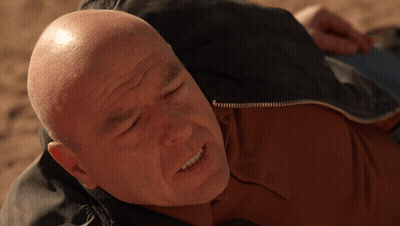 Bald Man In Brown Shirt Laying On Ground GIF