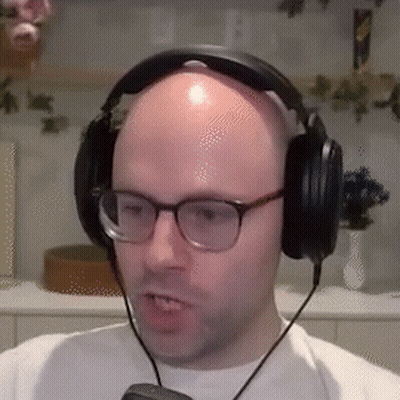 Bald Man In Glasses And Headphones Looking At Camera GIF