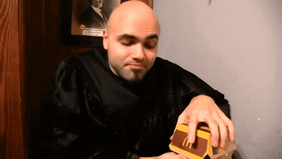 Bald Man In Graduation Gown Eating McDonald's Hamburger GIF