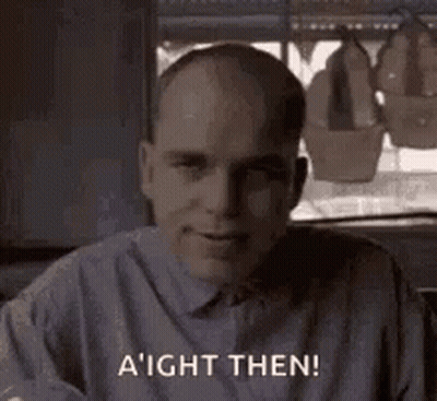Bald Man In Gray Shirt Smiling By Window GIF