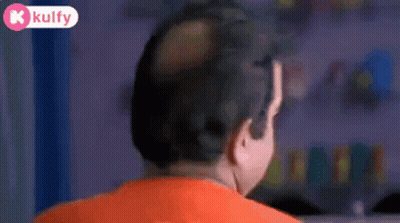 Bald Man In Orange Shirt Looking At Camera GIF