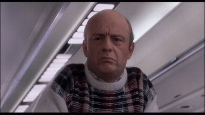 Bald Man In Plaid Sweater Looking At Camera GIF