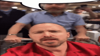 Bald Man In Red Shirt Pushed By Another Man GIF
