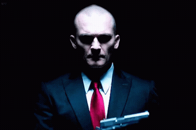 Bald Man In Suit And Tie Holding Gun GIF
