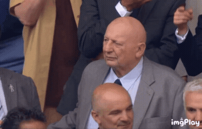 Bald Man In Suit And Tie Sitting In Crowd GIF