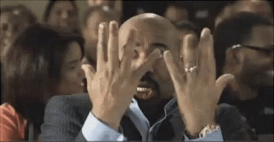 Bald Man In Suit Covering Face In Crowd GIF