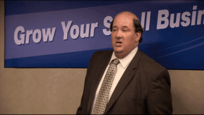 Bald Man In Suit In Front Of Grow Your Small Business Sign GIF