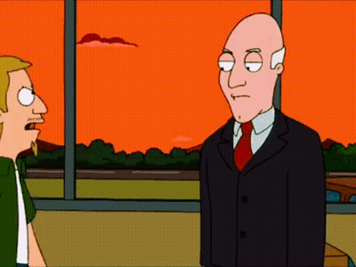 Bald Man In Suit Next To Blonde Man In Green Shirt GIF