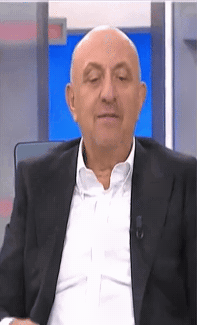 Bald Man In Suit Sitting In Front Of Blue Screen GIF