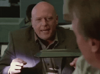 Bald Man In Suit Smiling In Front Of Lamp GIF