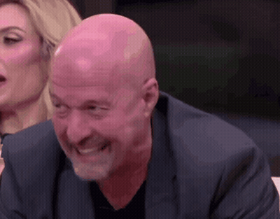Bald Man In Suit Smiling With Woman In Background GIF