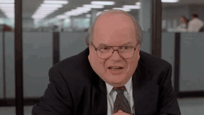 Bald Man In Suit, Tie, And Glasses At Desk GIF