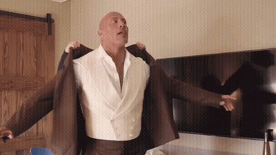 Bald Man In White Shirt And Brown Jacket Standing In Front Of TV GIF