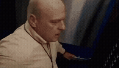 Bald Man In White Shirt Standing Next To Woman GIF