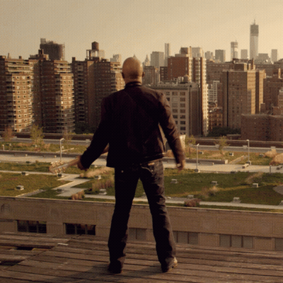 Bald Man On Rooftop Overlooking City Skyline GIF