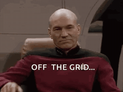 Bald Man Sitting In Chair With Off The Grid Shirt GIF