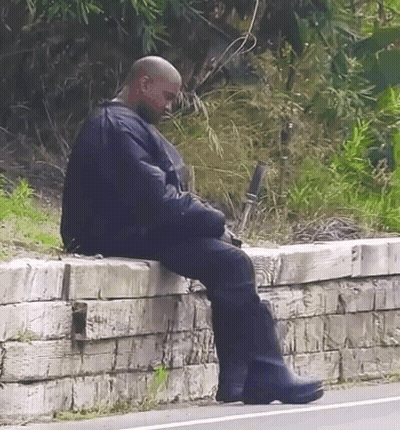 Bald Man Sitting On Brick Wall GIF