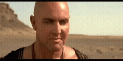 Bald Man Standing In Desert Looking At Camera GIF
