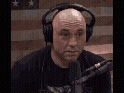 Bald Man Talking Into Microphone Near American Flag GIF