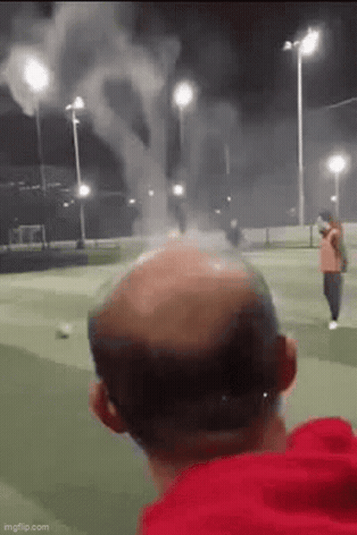 Bald Man Watching Fireworks On Soccer Field At Night GIF
