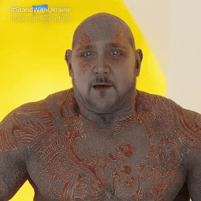 Bald Man With Beard And Chest Tattoos In Front Of Yellow Wall GIF