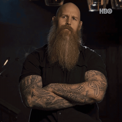 Bald Man With Beard And Tattoos Arms Crossed In Front Of HBO Logo GIF