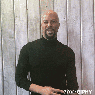 Bald Man With Beard In Black Turtleneck Standing In Front Of Wooden Wall GIF
