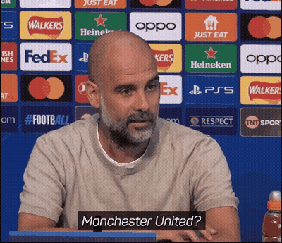 Bald Man With Beard Sitting In Front Of Manchester United Sign GIF