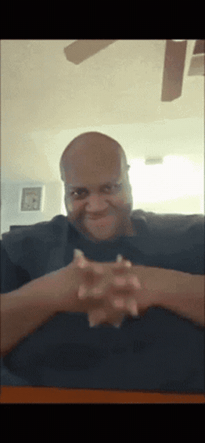 Bald Man With Hands Folded At Table GIF