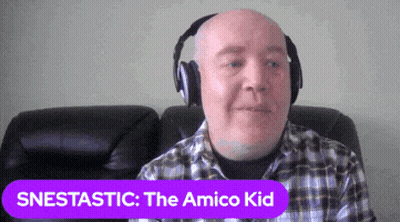 Bald Man With Headphones Sitting On Couch With Purple Snestastic Amico Kid Sign GIF