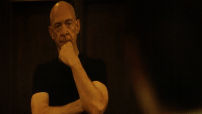Bald Man With Mustache Looking At Camera In Dark GIF