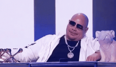 Bald Man With Sunglasses And Necklace Sitting Beside Dog Statue GIF