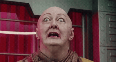 Bald Woman Making Funny Face In Front Of Red Curtain GIF