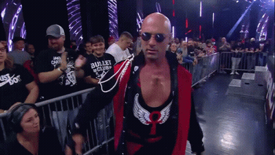 Bald Wrestler In Sunglasses And Red Vest Walking Through Crowd GIF