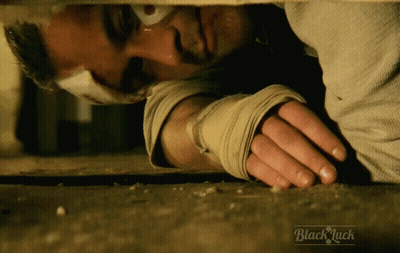 Bandaged Man Lying On Ground Saying Black Luck GIF